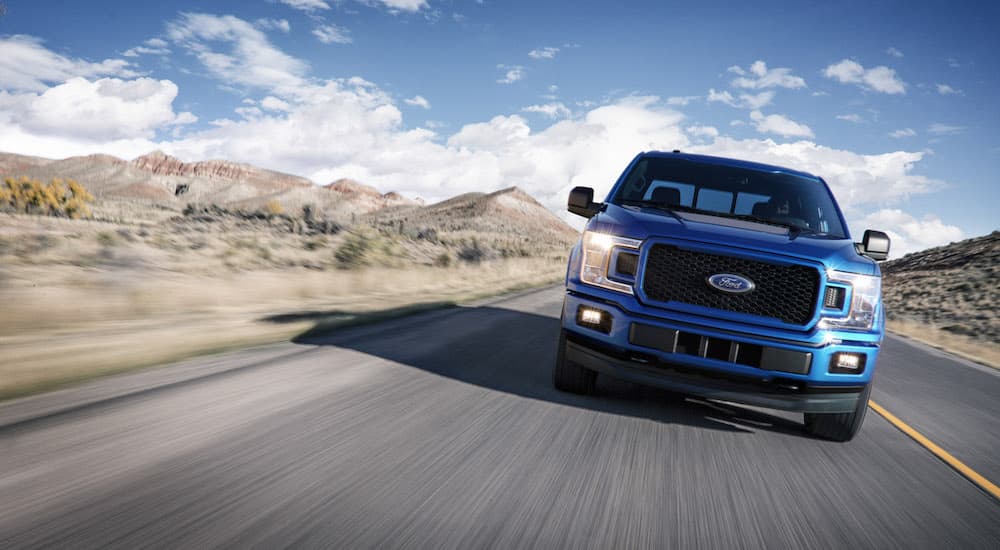 Blue 2018 Ford F-150 driving down an open road.