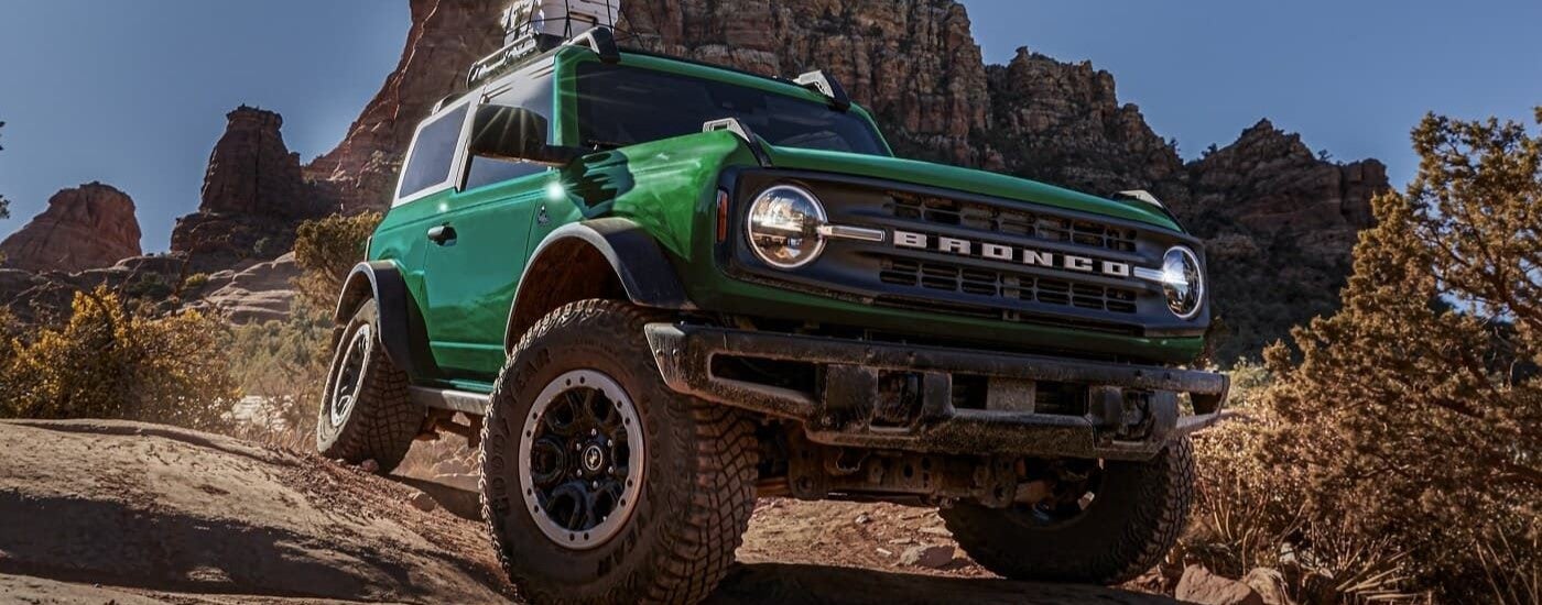 Green 2026 Ford Bronco driving off-road down a hill.