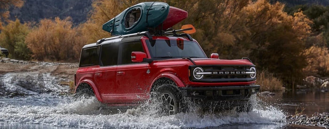 Red 2026 Ford Bronco driving through a shallow river.