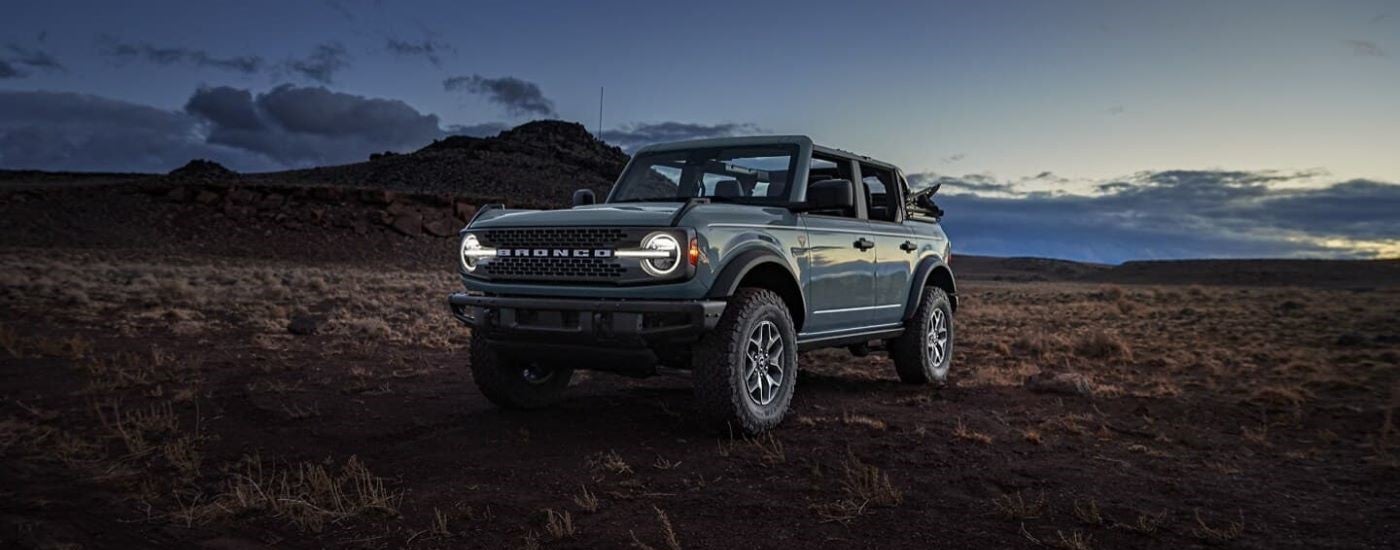Green 2026 Ford Bronco driving off-road down a hill.