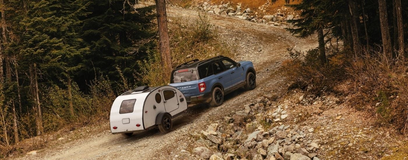 Blue 2025 Ford Bronco Sport Badlands towing a camper off-road