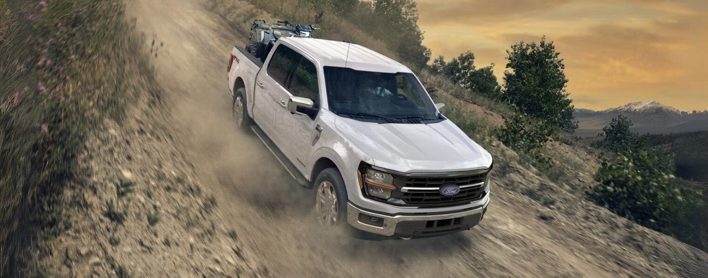 White 2025 Ford F-150 XLT driving down a dusty hill