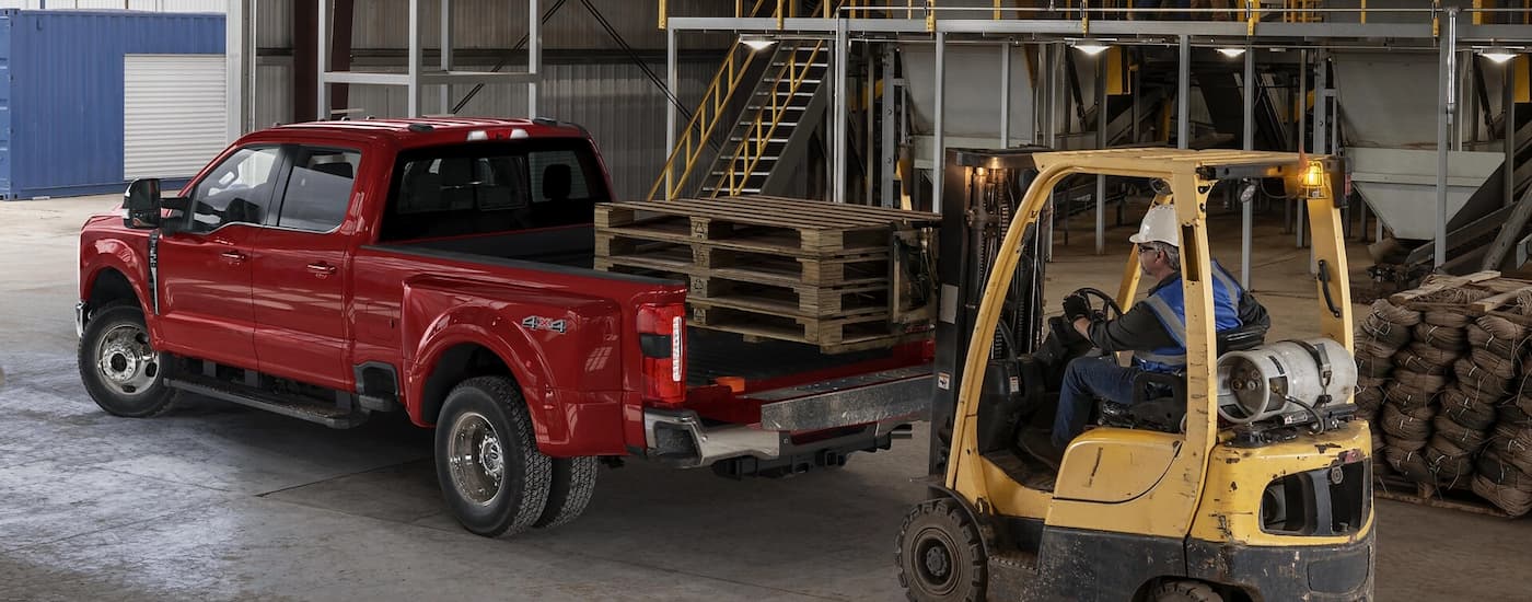 Rear of a red 2025 Ford F-350 hauling pallets in a warehouse.