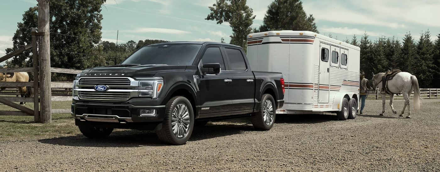 Black 2026 Ford F-150 towing a trailer on a farm.