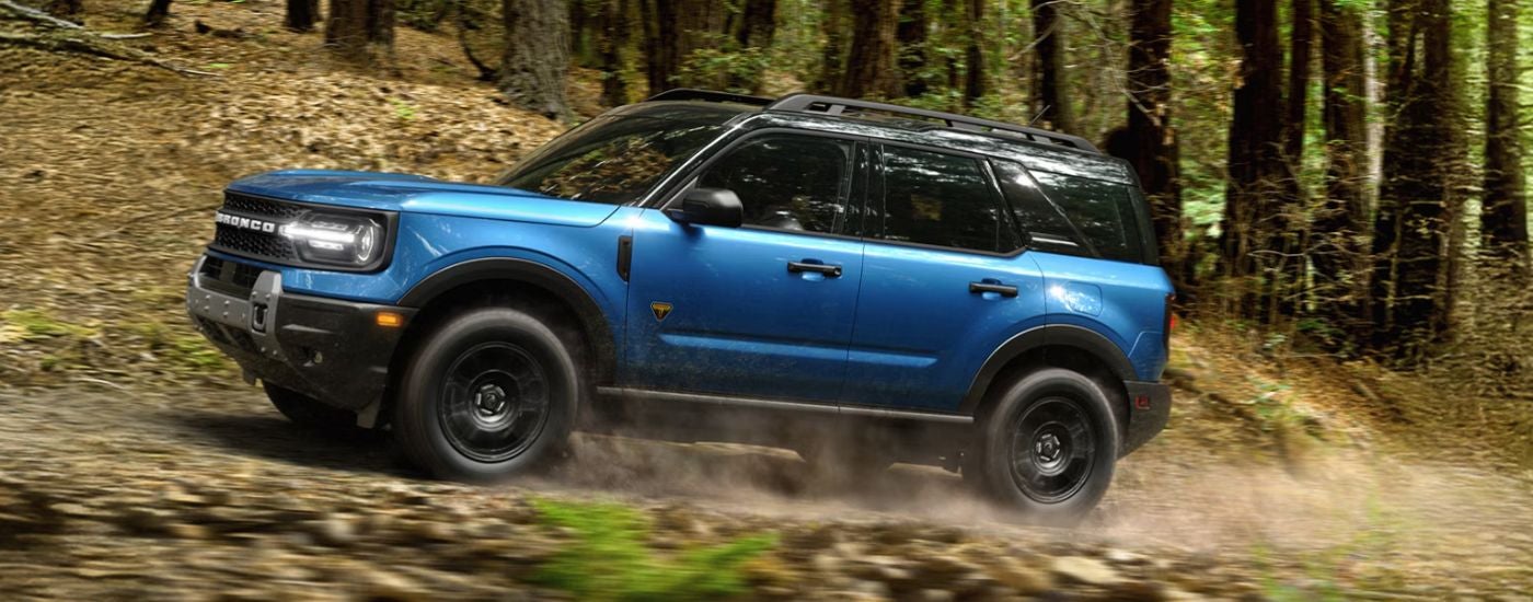 Blue 2026 Ford Bronco Sport driving off-road through the woods.