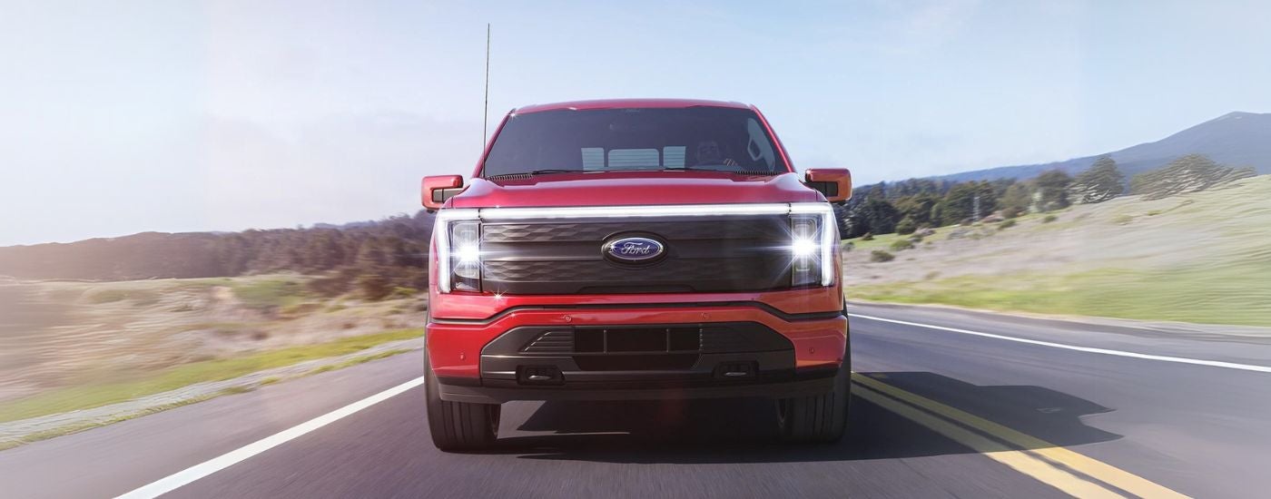 A red 2023 Ford F-150 Lightning driving head-on.