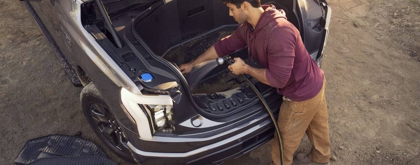 A person cleaning the frunk of a grey 2023 Ford F-150 Lightning.