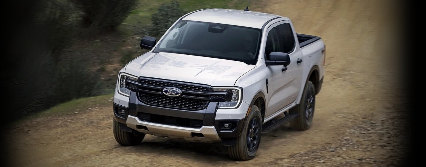 A white 2024 Ford Ranger driving to a Ford dealer.
