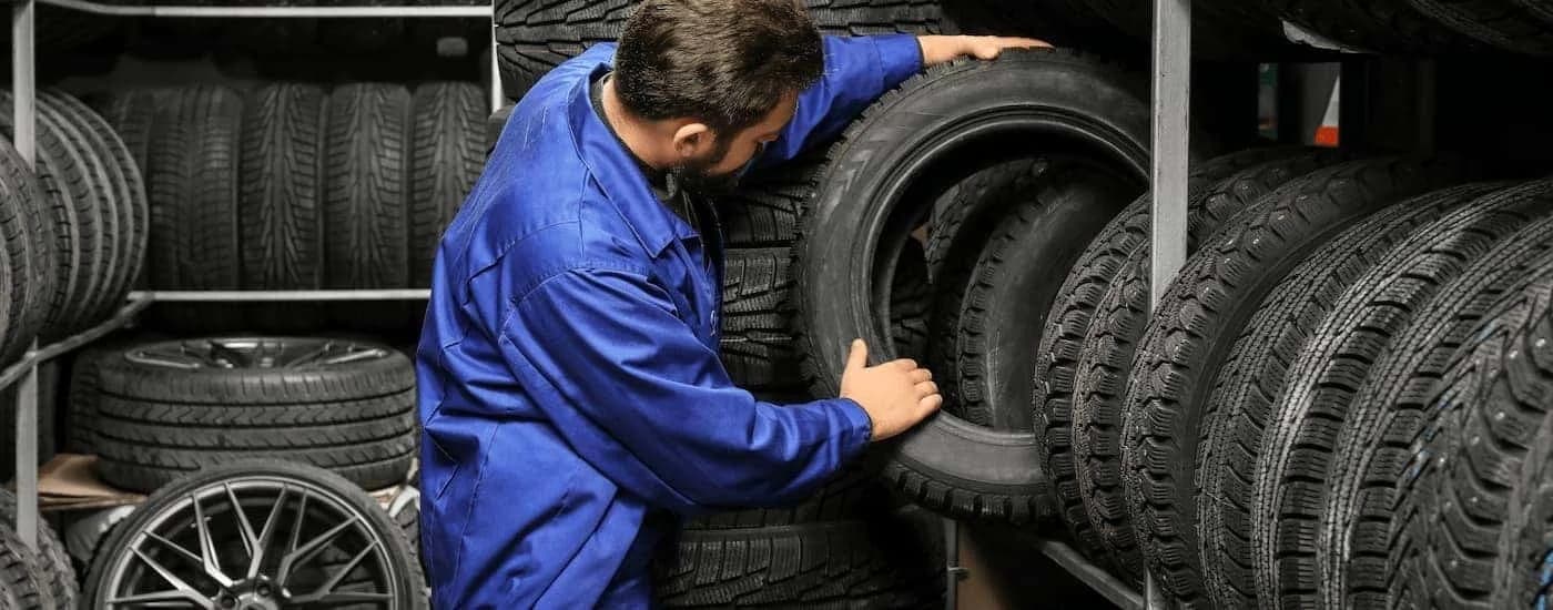 Mechanic pulling tires off a rack.