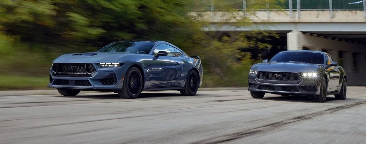 A blue and a gray 2024 Ford Mustang Dark Horse and GT driving on a highway