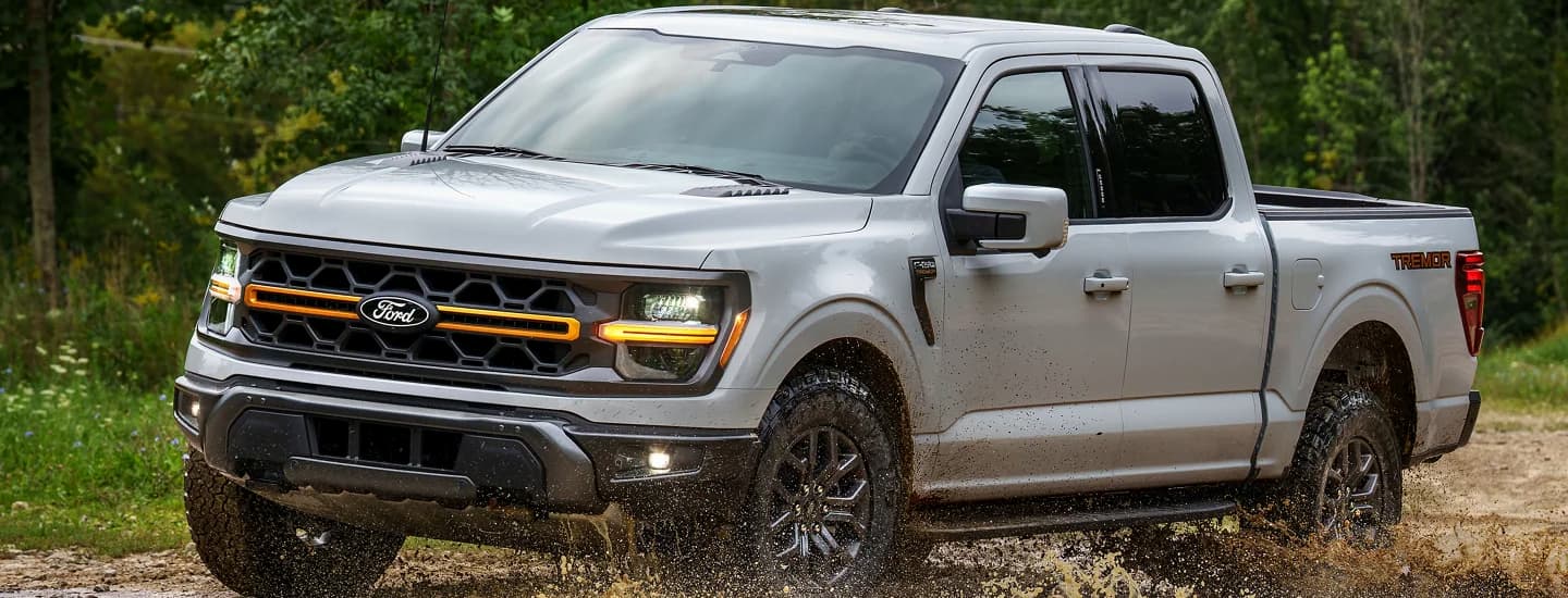 A gray 2025 Ford F-150 off-roading in mud